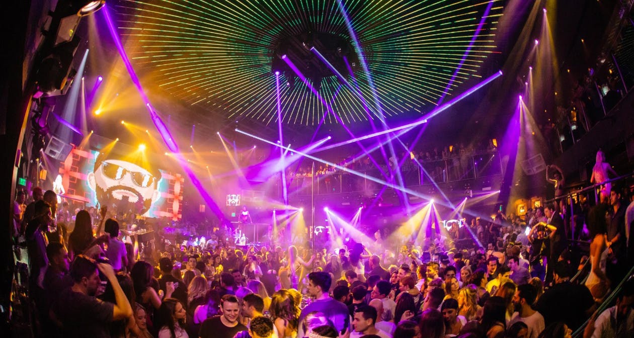 Área ao ar livre da Sky Yard Nightclub em Miami, decorada com luzes de festa que criam uma atmosfera intimista e charmosa. Grupos de pessoas estão sentados em mesas, aproveitando a noite, com a vista da cidade ao fundo.