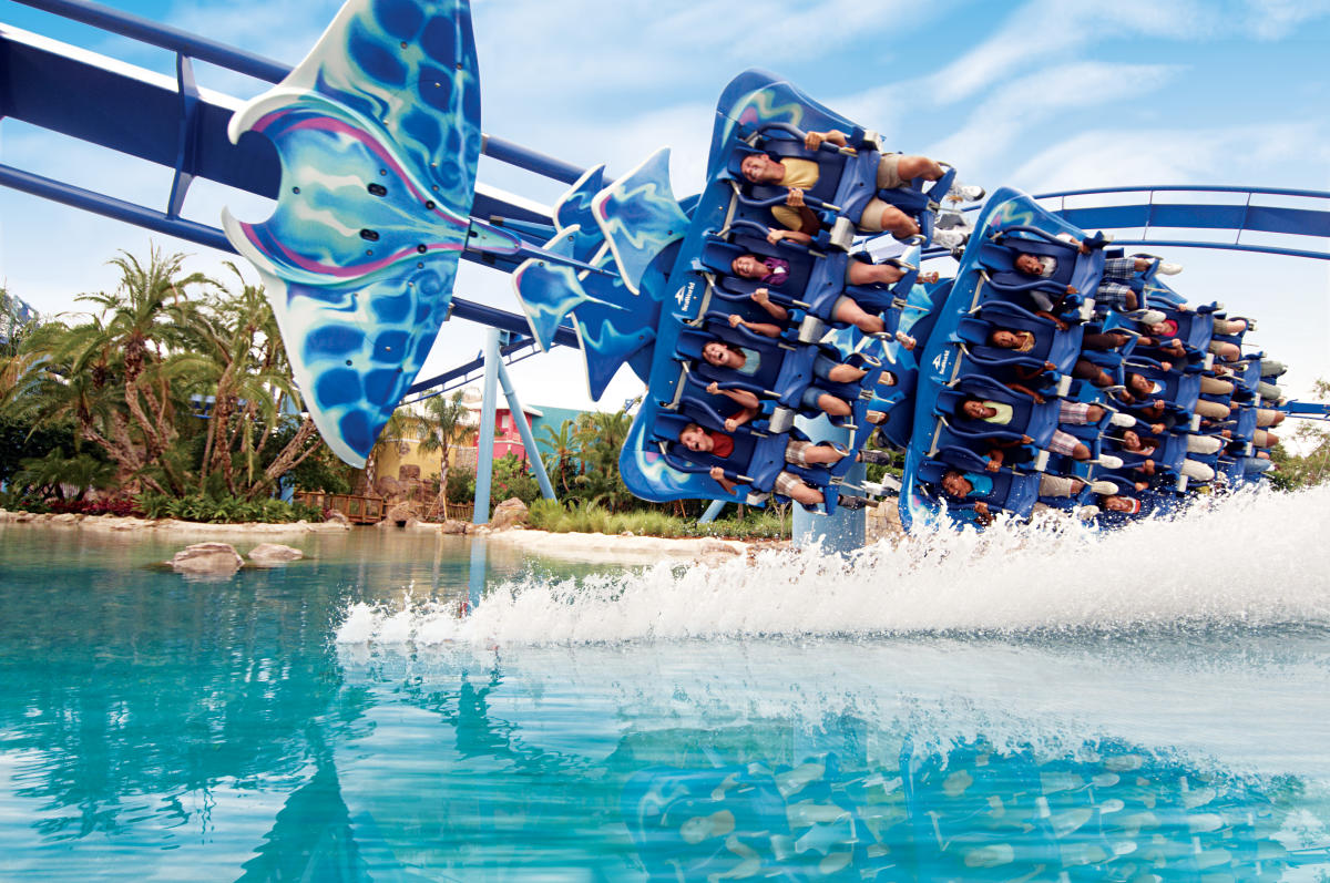 Montanha-russa Manta no SeaWorld Orlando, com visitantes a bordo em uma posição de voo, passando perto da água enquanto desfrutam de um passeio emocionante.